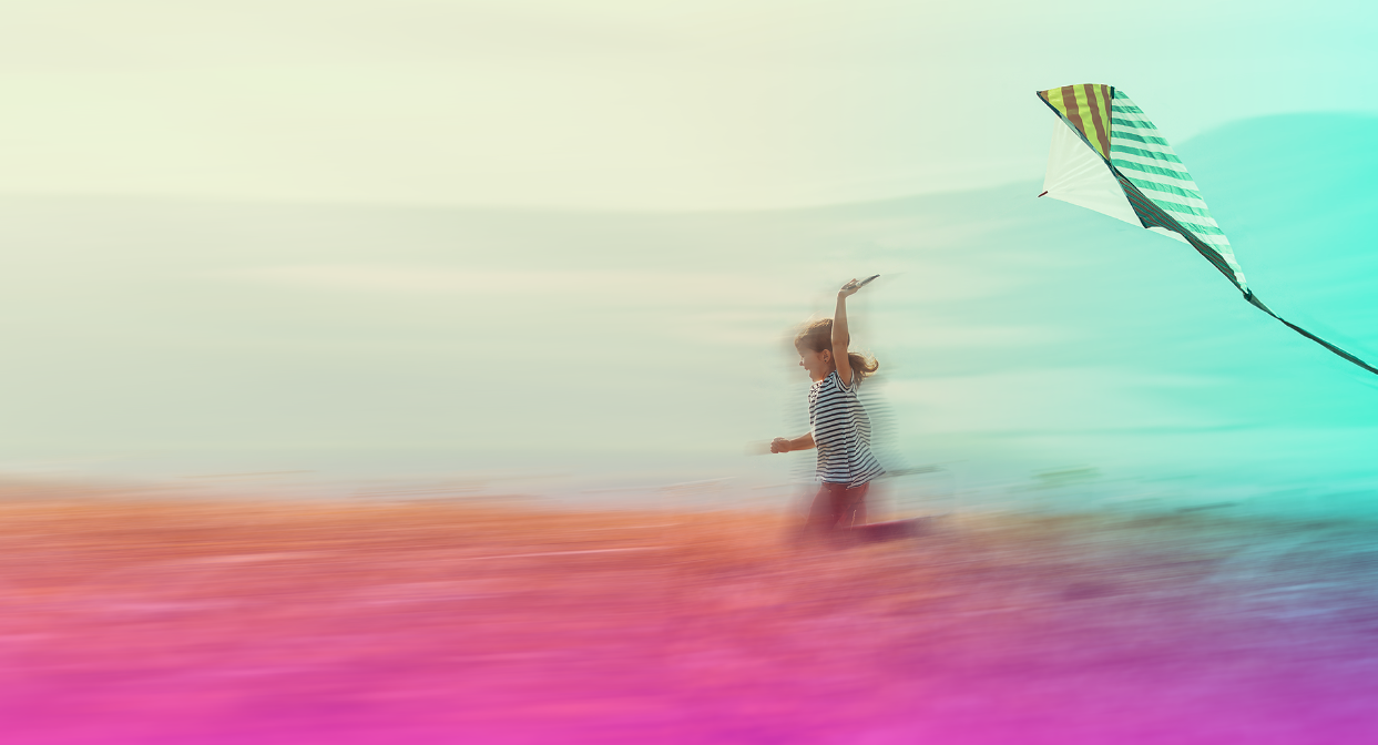 A child running through a field flying a kite.