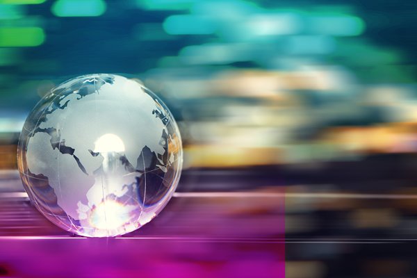A glass transparent globe resting on a table reflecting light.
