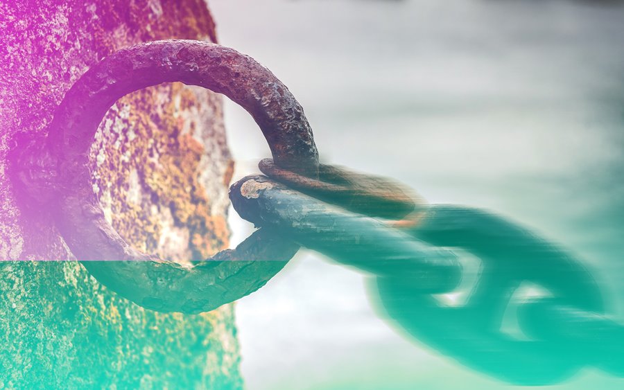 A rusty chain held onto a wall.