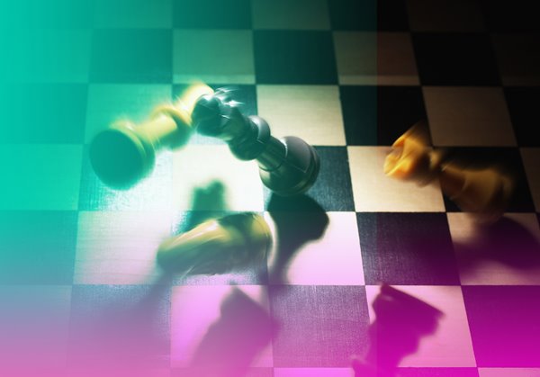 Chess pieces falling over in motion on a chess board.