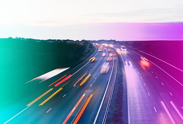 A six lane motorway with cars in motion.