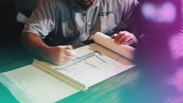 An architect looking at building drawings on a desk.
