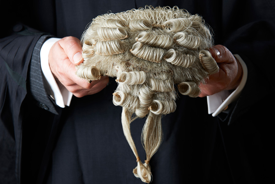 A man holding a barrister's wig.