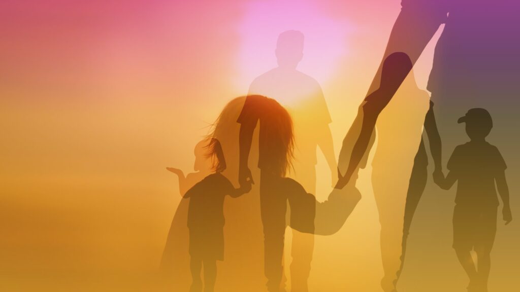 A family holding hands walking towards the sun.