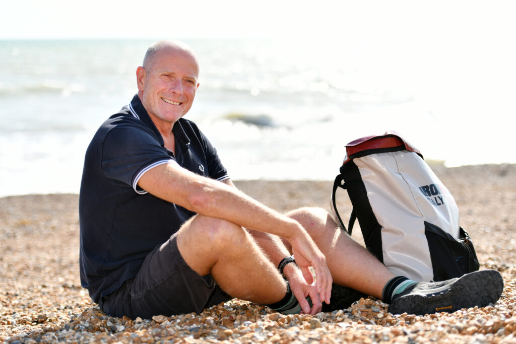 DMH Stallard Partner, David Bailey, sitting on the beach in preparation for English Channel charity swim