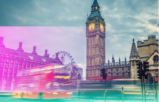 Big Ben with a red London bus driving past.
